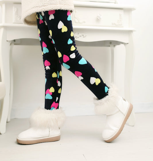 Kids' black leggings with colorful hearts, paired with white fuzzy boots for cozy winter fashion