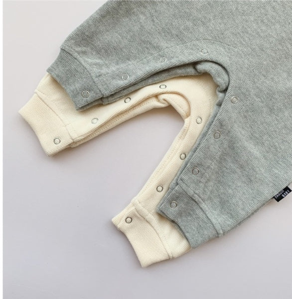 Soft gray and cream baby onesies with snap closures, cozy infant clothing for newborns