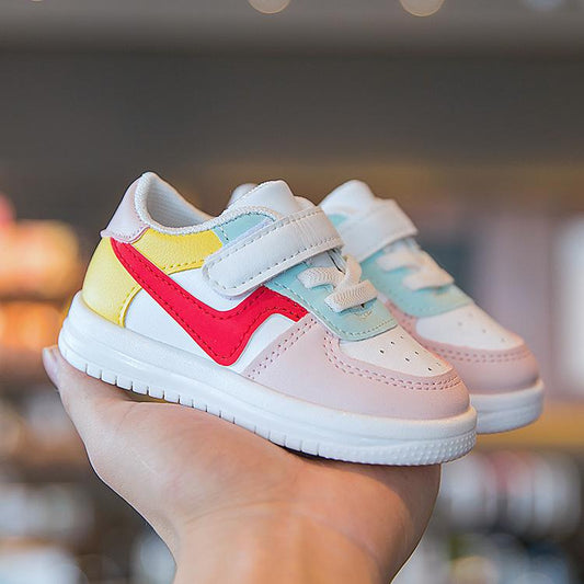 Colorful toddler sneakers with velcro straps, pastel pink, red, yellow, and mint accents, held in hand