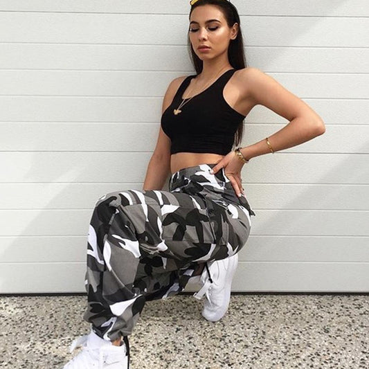 Woman in black crop top and camo cargo pants, styled with white sneakers for casual streetwear fashion