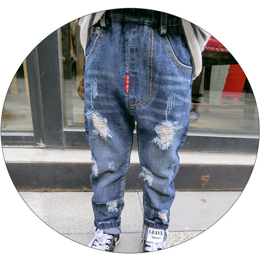 Ripped children's jeans in blue denim with distressed details, branded by Ancient Energy, shown on a child.