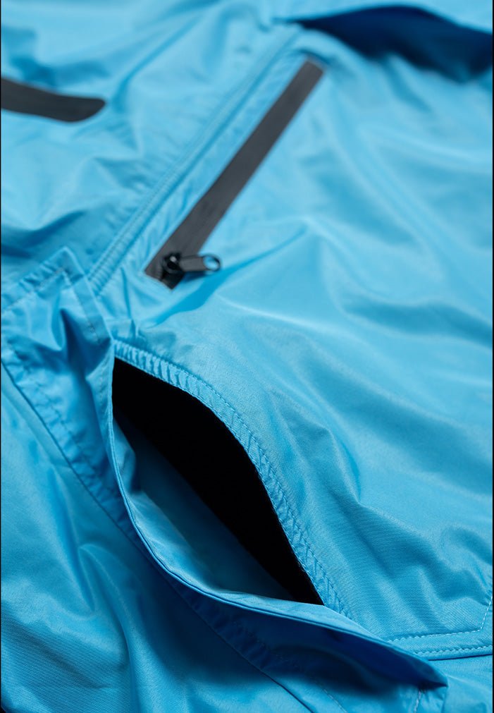 IWOM WeatherShield Convertible Jacket shown outdoors with adjustable hood and multiple zippered pockets for versatile weather protection.