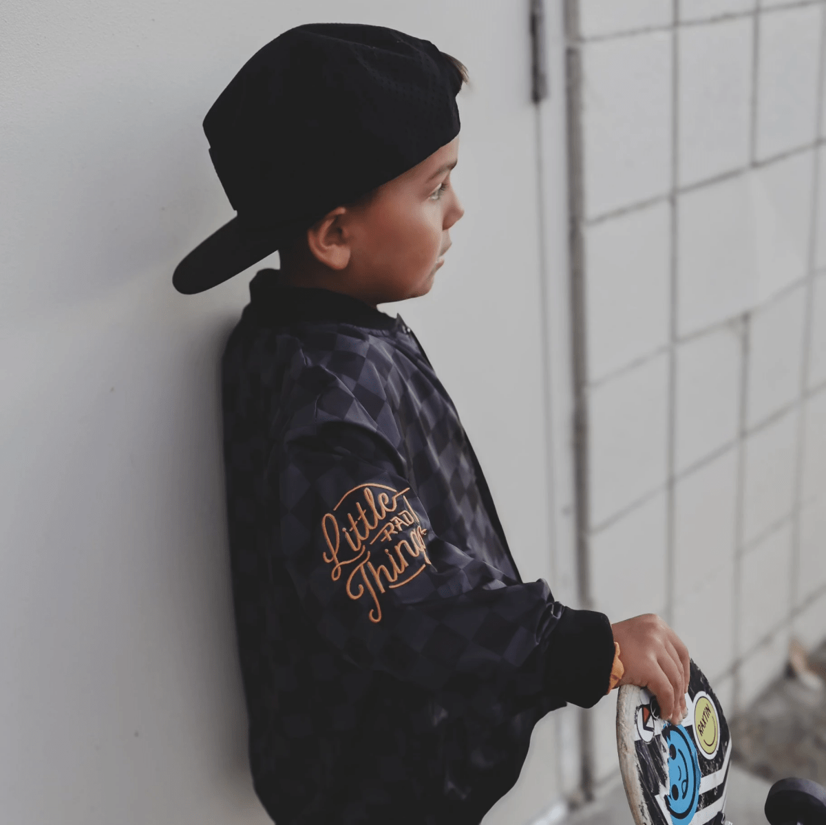 Kids waterproof letterman jacket by Little Rad Things with checkered pattern, featuring a warm, durable outer layer.