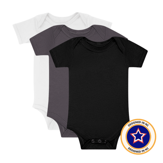 Set of three Little Rad Things neutral monochrome onesies, soft and comfortable baby clothing in various minimalist designs.