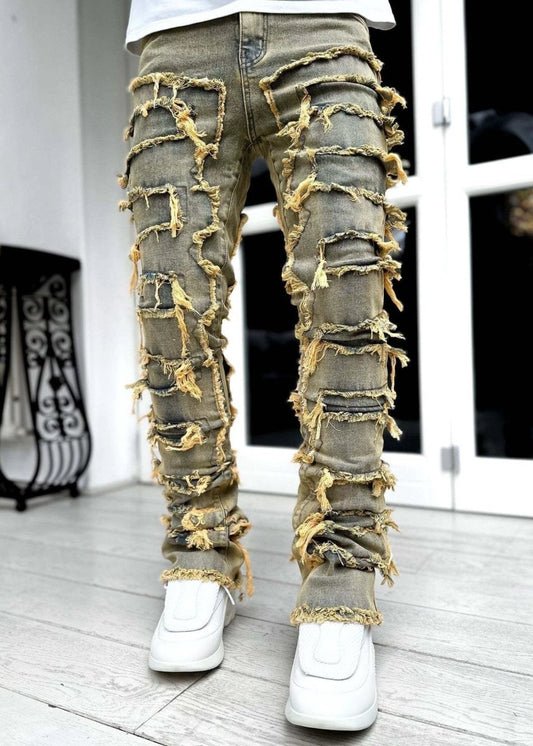 Men's stacked jeans by MANDOTOS featuring patched designs and a long, tight fit for a bold style.
