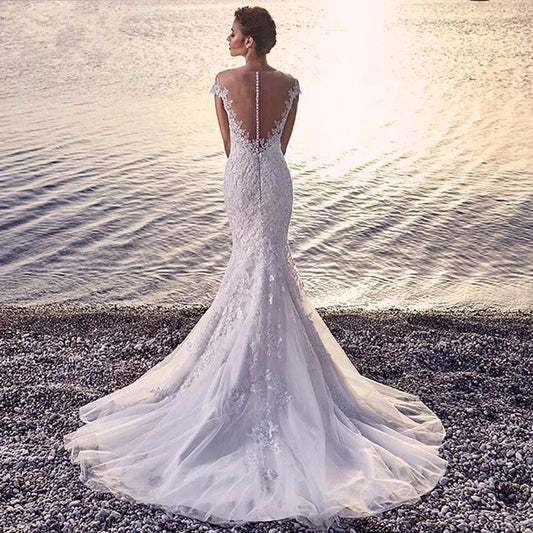 Mandotos Princess Bride mermaid wedding dress in white with trailing backless lace design and elegant fit.