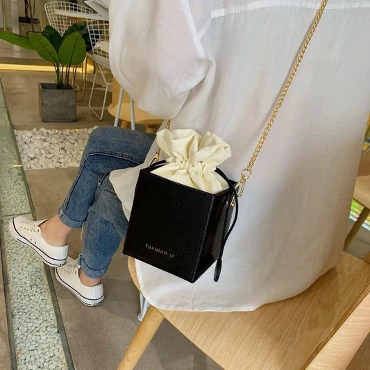 Mandotos chic alligator pattern bucket bag with adjustable shoulder strap and gold-tone hardware on a white background.