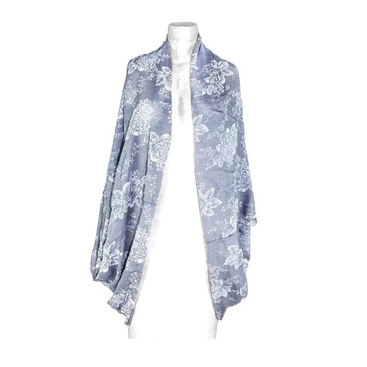 Mandotos denim blossom poncho featuring floral embroidery and lightweight denim fabric, styled with a relaxed fit and fringed edges.