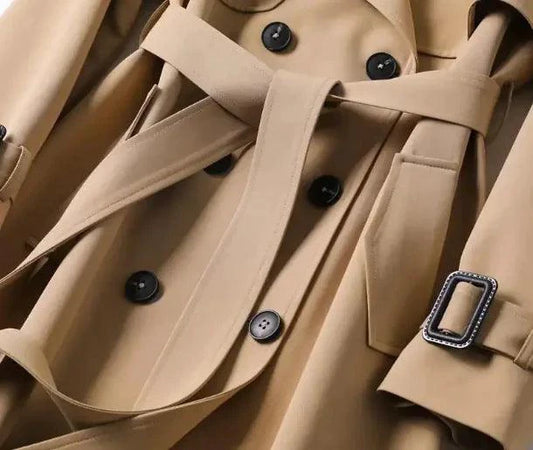 Mandotos elegant classic trench coat displayed on a hanger, featuring a timeless design and neutral color for sophisticated style.