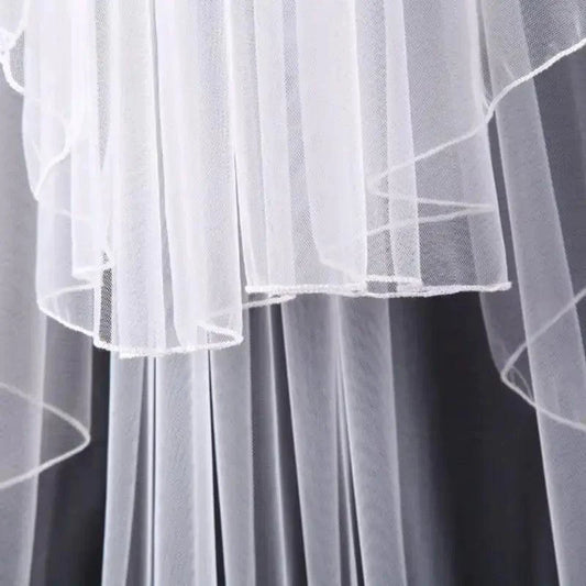 Ethereal double-tiered veil by MANDOTOS featuring delicate lace and sheer fabric, perfect for bridal or special occasion wear.