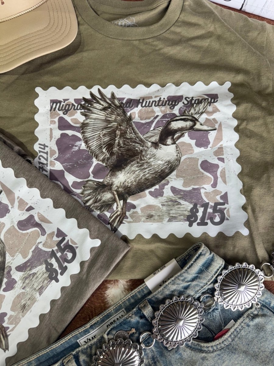 Olive green Duck Stamp graphic tee by Wild Junkie featuring a detailed duck stamp design on a casual men's graphic T-shirt.