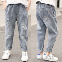 Kids' distressed denim jeans with ripped details, cuffed hems, and white sneakers for casual fashion