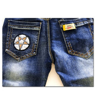 Blue denim jeans with star patch and yellow brand tag on back pockets, fashion apparel