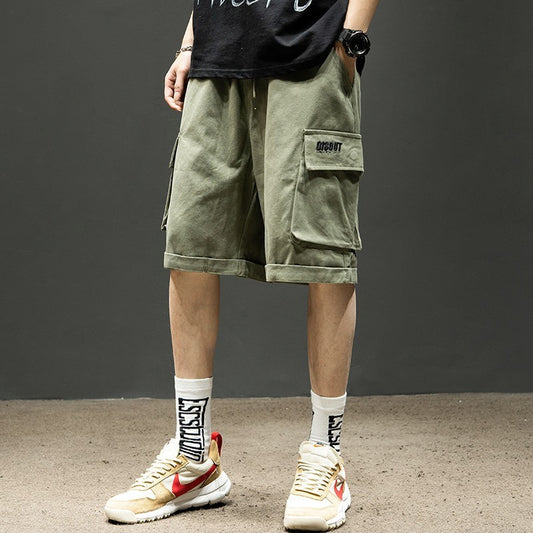 Men's olive cargo shorts with pockets, paired with graphic socks and sneakers for casual streetwear style