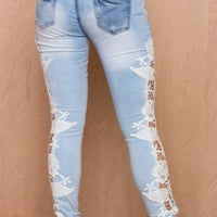 Light blue distressed jeans with white lace floral detailing on legs, fashion denim wear