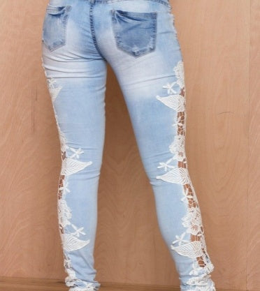 Light blue distressed jeans with white lace floral detailing on legs, fashion denim wear