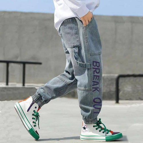 Stylish cargo jeans with 'BREAK OUT' print, paired with colorful high-top sneakers for urban streetwear fashion