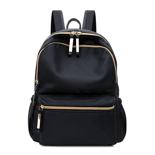 Black backpack with gold zippers, sleek design for fashion and travel