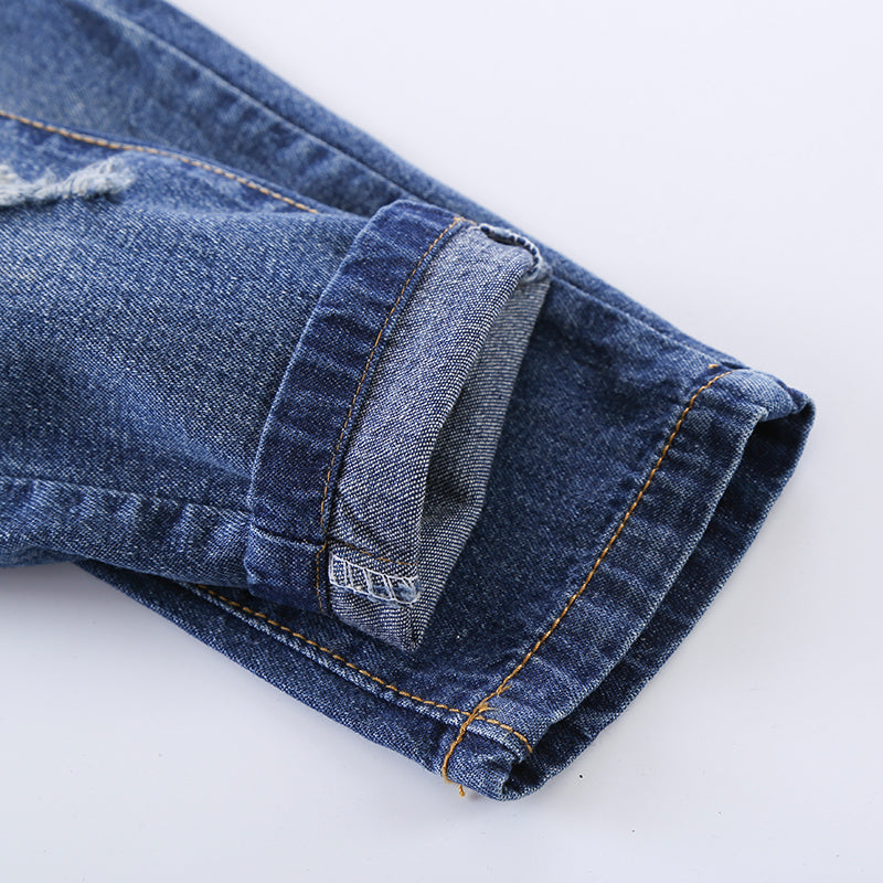Distressed blue denim jeans with rolled cuff and orange stitching, premium fashion wear