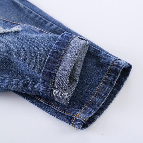 Distressed blue denim jeans with rolled cuff and orange stitching, premium fashion wear