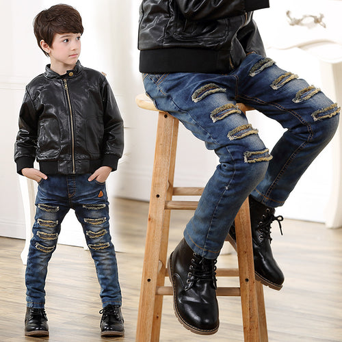 Boy in black leather jacket and ripped blue jeans, stylish kids fashion outfit