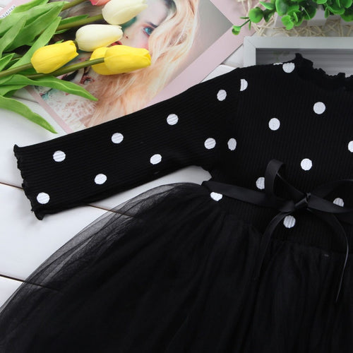 Black polka dot dress with tulle skirt and ribbon bow, styled with yellow tulips