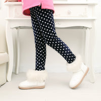 Child wearing navy polka dot leggings with white fur-trimmed boots, cozy winter fashion
