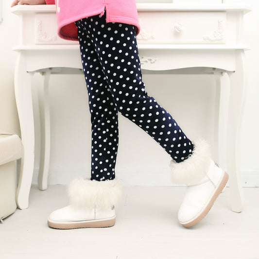 Child wearing navy polka dot leggings with white fur-trimmed boots, cozy winter fashion