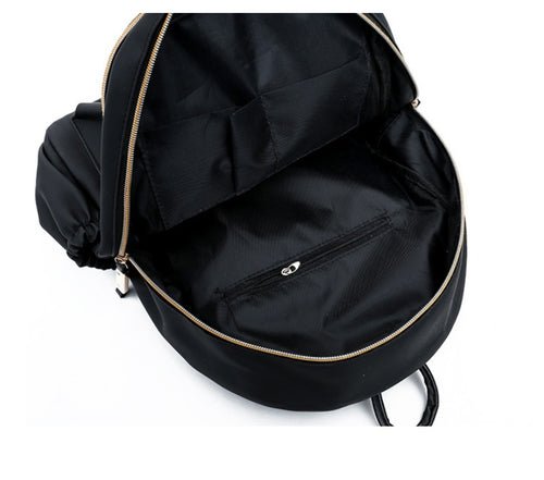 Black backpack interior with gold zipper and front pocket, ideal for fashion accessories and daily essentials