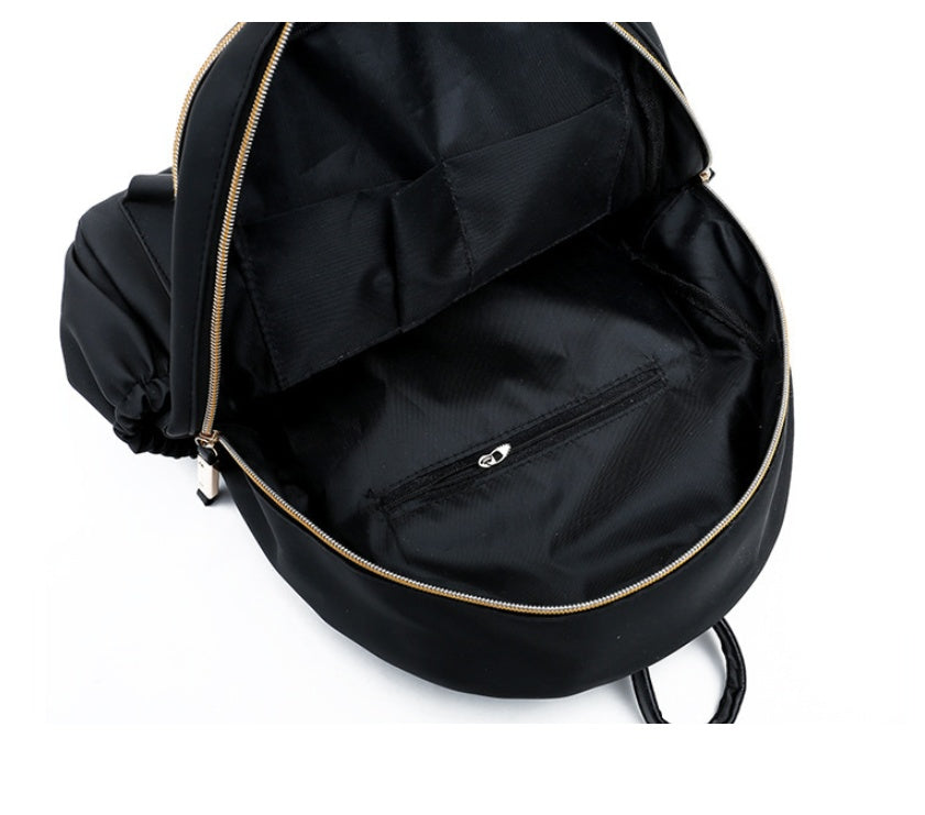 Black backpack interior with gold zipper and front pocket, ideal for fashion accessories and daily essentials