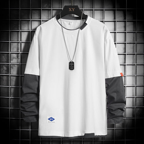 White long-sleeve color-block t-shirt with black sleeves, dog tag necklace, displayed on hanger against grid wall