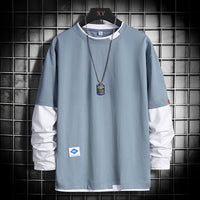 Light blue long-sleeve shirt with white accents, dog tag necklace, and grid background