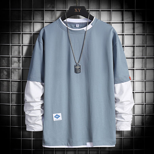 Light blue long-sleeve shirt with white accents, dog tag necklace, and grid background
