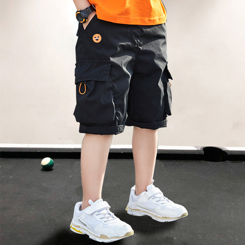 Black cargo shorts with smiley patch, worn with white sneakers and orange tee for kids' casual fashion