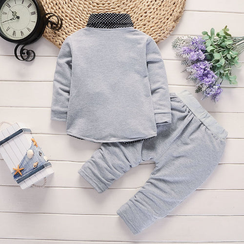 Gray baby outfit with polka dot collar, soft long sleeve top and matching pants, styled with flowers and clock