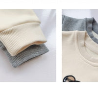 Cream and gray baby long-sleeve onesies with ribbed cuffs and snap buttons, soft cotton fabric