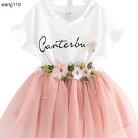 White V-neck dress with 'Canterbury' script, pink tulle skirt, floral embroidery, and pearl accents