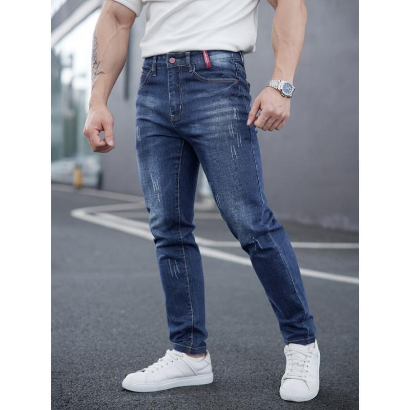 Men's ripped denim jeans with cat-whisker scratches from Ancient Energy, showcasing distressed style and casual fit.