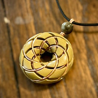 Brass Torus Vortex pendant with Libyan Desert Glass Orgonite necklace and Rodin Coil by Ancient Energy, close-up view of the jewelry piece.