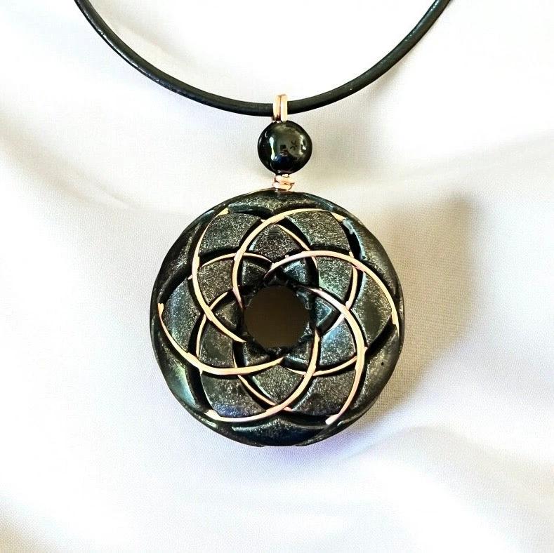 Ancient Energy Torus Vortex pendant necklace featuring Shungite orgonite and Rodin coil design, resting against a neutral background.