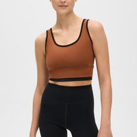 Elastique Athletics Lisse Bra in chestnut and black, shown as a stylish, fitted sports top for active wear.