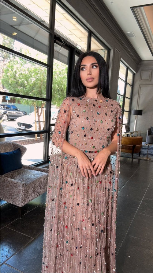 Multi-color beaded modest gown with cape sleeves, A-line silhouette, by Iyza Belaar, featuring intricate embroidery and elegant design.