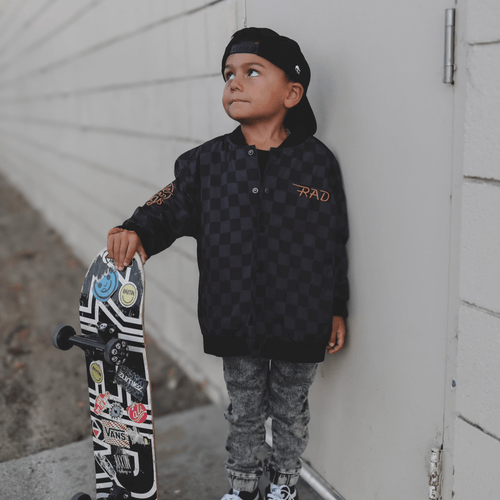 Kids waterproof letterman jacket by Little Rad Things with checkered design, featuring a sporty style and vibrant colors.