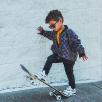 Kids waterproof letterman jacket by Little Rad Things with a checkers pattern and ribbed cuffs, perfect for rainy days.
