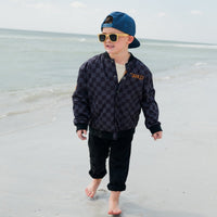 Kids waterproof letterman jacket by Little Rad Things with checkered pattern, featuring a sporty, colorful design.