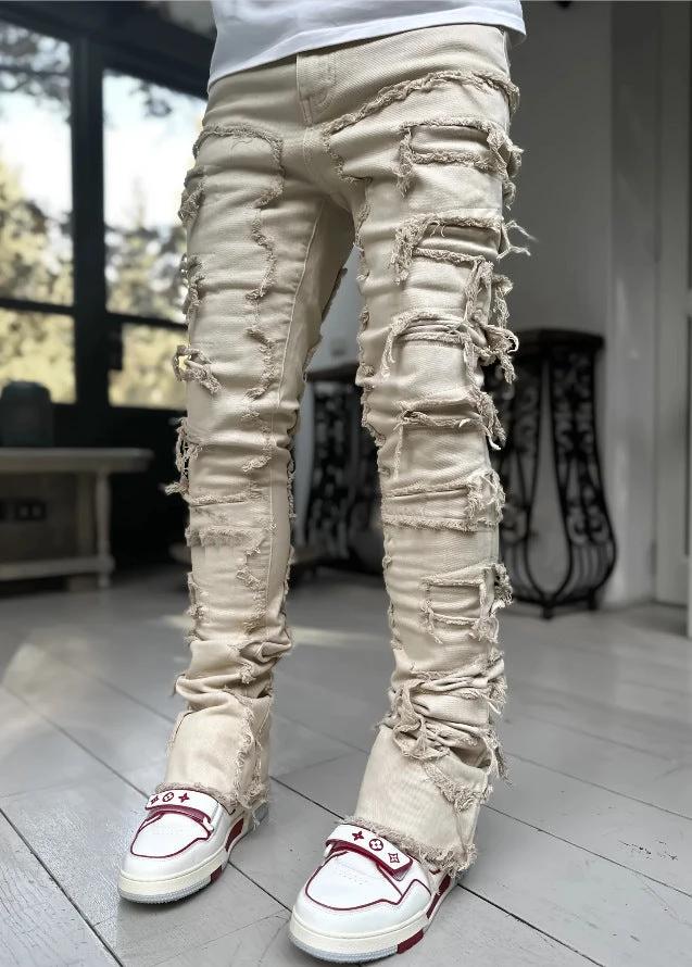 Men's stacked jeans by MANDOTOS featuring patched details, long tight fit trousers with bold style and modern denim design.
