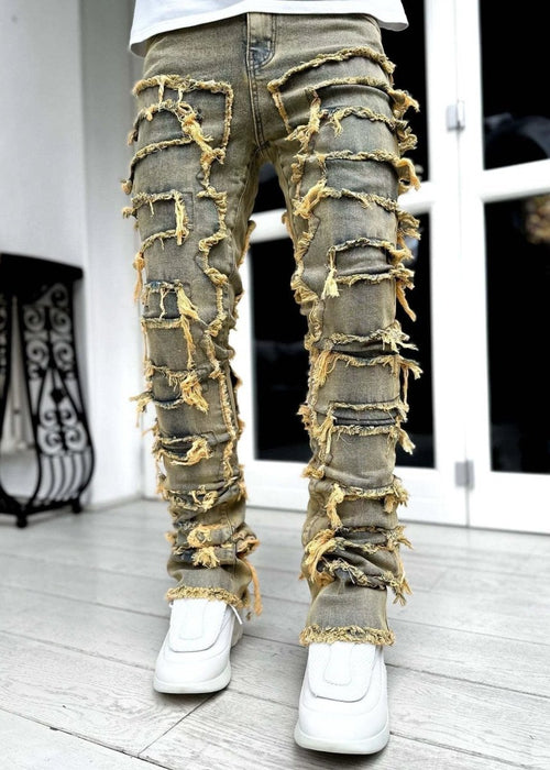 Men's stacked jeans by MANDOTOS featuring patched designs and a long, tight fit for a bold style.