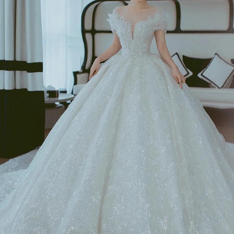 Off-shoulder French main wedding dress by MANDOTOS featuring elegant lace details and a flowing train.