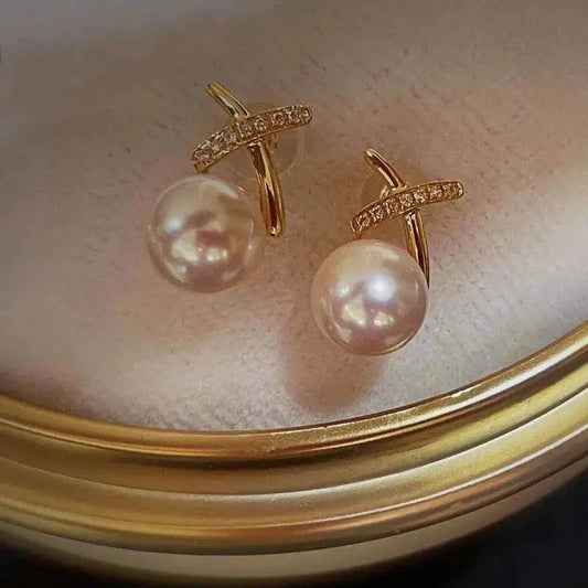 18K gold pearl stud earrings by MANDOTOS featuring elegant round pearls on classic gold posts.