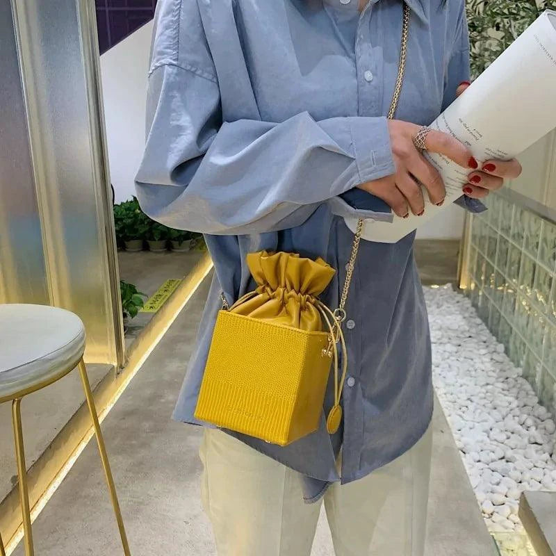 Mandotos chic alligator pattern bucket bag with gold-tone hardware and adjustable strap, stylish accessory for casual and formal outfits.